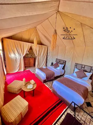 a group of four beds in a tent at Merzouga Camp & Events in Merzouga