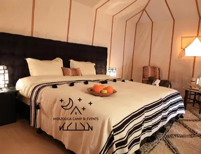 a bedroom with a bed with a bowl of fruit on it at Merzouga Camp & Events in Merzouga