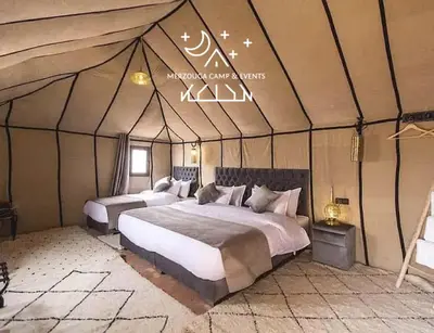 a bedroom with two beds in a tent at Merzouga Camp & Events in Merzouga