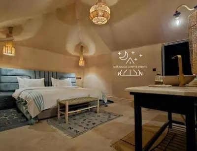 a bedroom with a bed and a table and a desk at Merzouga Camp & Events in Merzouga