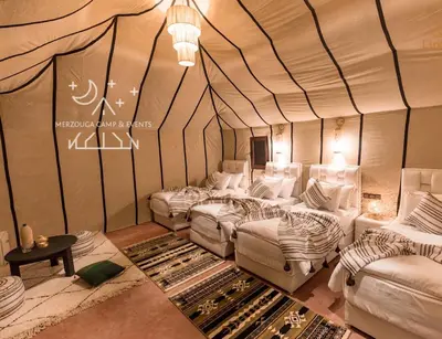 a room with four beds in a tent at Merzouga Camp & Events in Merzouga