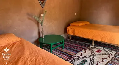 a room with two beds and a green table at Berber Oasis Camp in Kasr Bounou