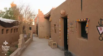 an alley between two buildings with tables and chairs at Berber Oasis Camp in Kasr Bounou