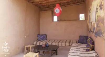 a room with two beds and a table in it at Berber Oasis Camp in Kasr Bounou