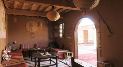 a living room with two tables and an open door at Berber Oasis Camp in Kasr Bounou