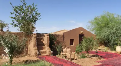 a man sitting on a bench in front of a house at Berber Oasis Camp in Kasr Bounou