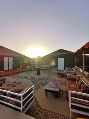 a living room with a large tent with the sun setting at Desert Camp in Zagora - Camel ride - Easy & Affordable Stays in Zagora
