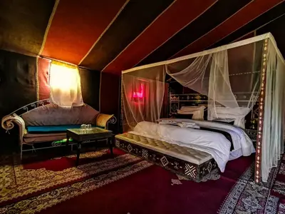 a bedroom with a canopy bed and a chair at Desert Camp in Zagora - Camel ride - Easy & Affordable Stays in Zagora
