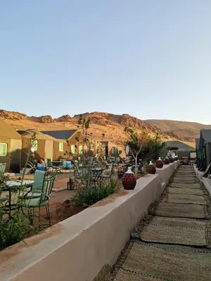 a retaining wall with chairs and tables in a yard at Desert Camp in Zagora - Camel ride - Easy & Affordable Stays in Zagora