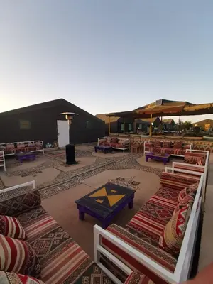 a group of tables and chairs in a room with carpet at Desert Camp in Zagora - Camel ride - Easy & Affordable Stays in Zagora