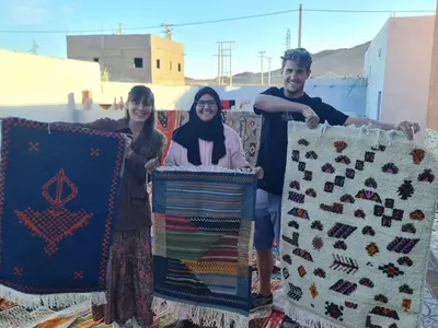 a group of three people holding up blankets at Espace Taznakhte in Tazenakht