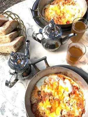 a table topped with two pans of food and bread at Espace Taznakhte in Tazenakht